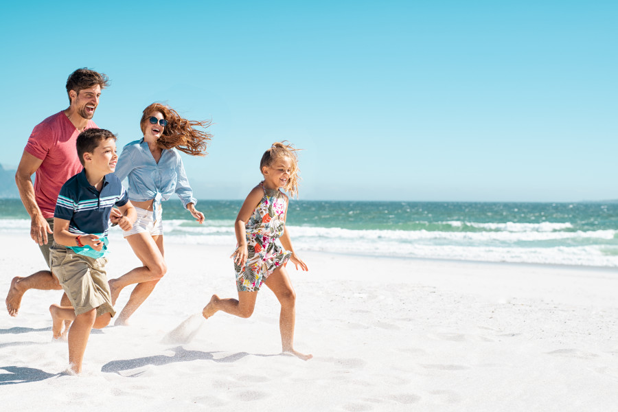 Glad familj springer på kritvit strand