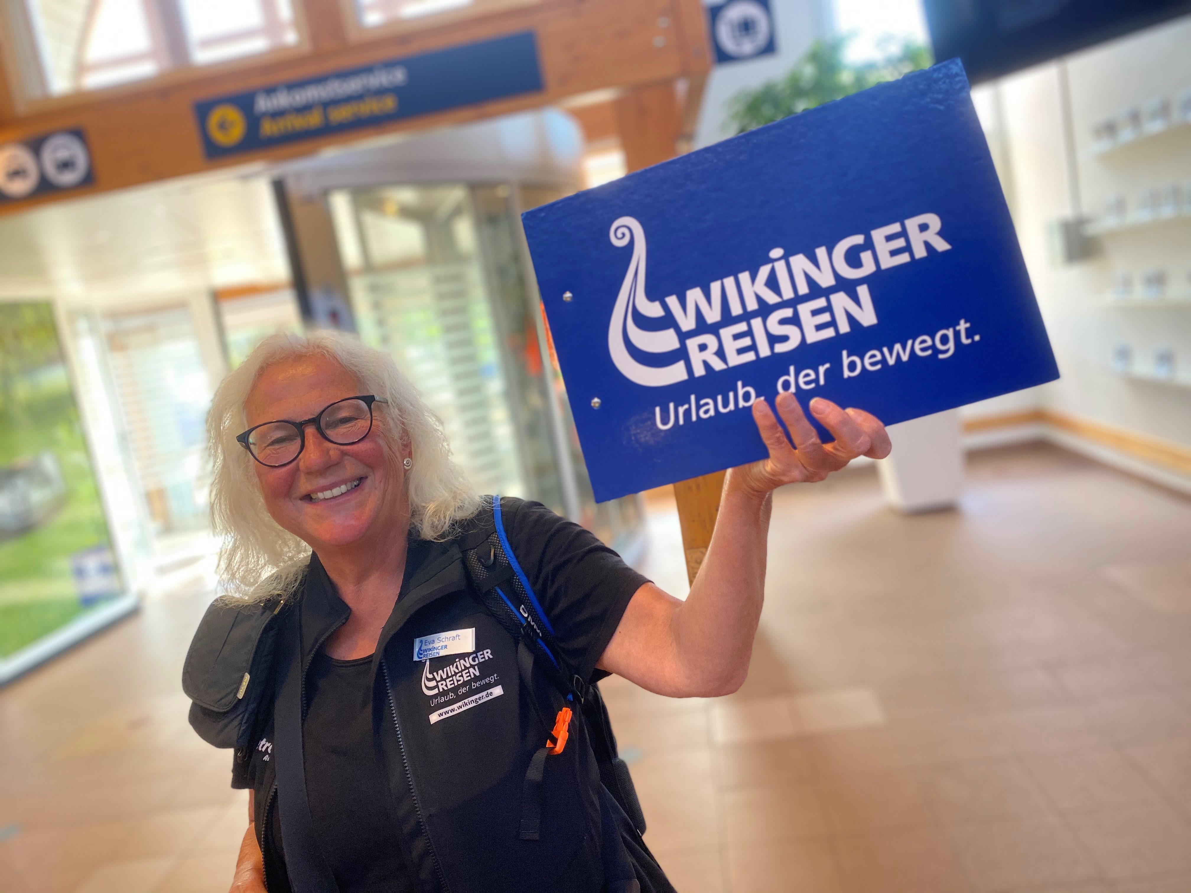 En representant för Wikinger Reisen håller upp en skylt i ankomsthallen