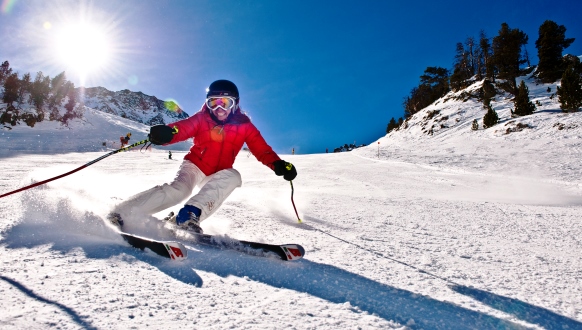 Skiers go slalom on a white slope in a sunny Andorra