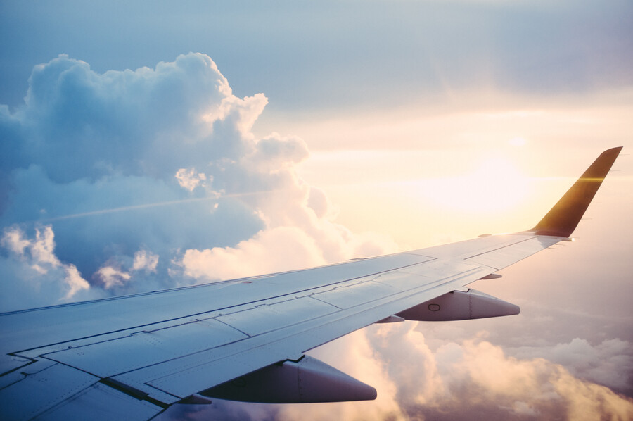 Flygplansvinge fotad från flygplansfönstret uppe bland molnen