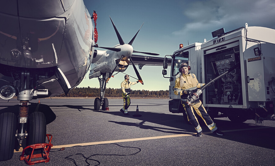 Kvinnlig medarbetare på väg att tanka propellerflygplan