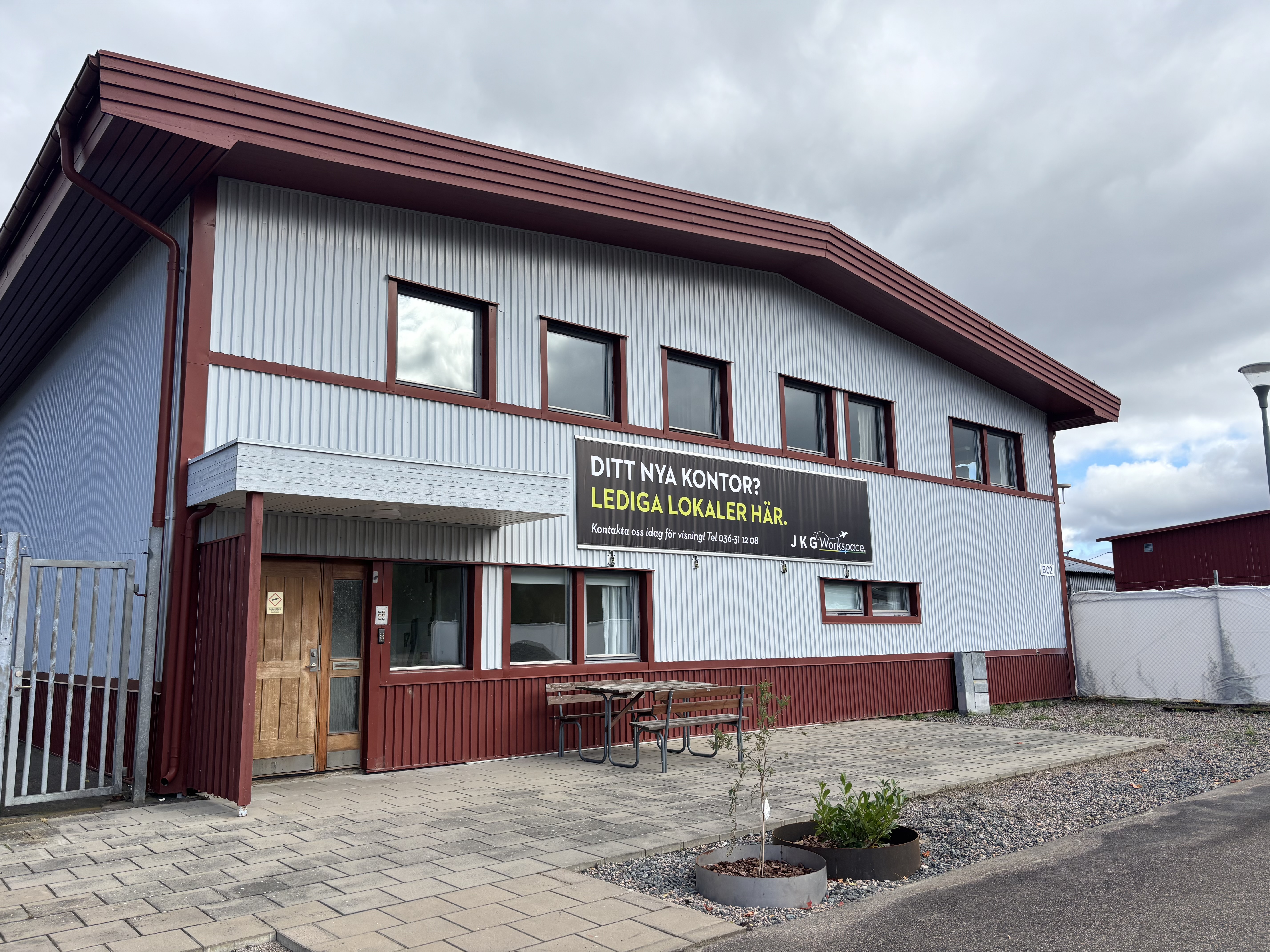 Byggnadens framsida med en vepa där det står att det finns lediga lokaler
